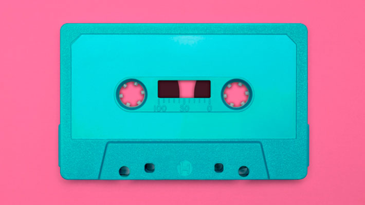 Nostalgic image of a blue cassette tape, isolated and presented on a pink background