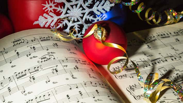 Sheet music surrounded with Christmas ornaments and ribbons