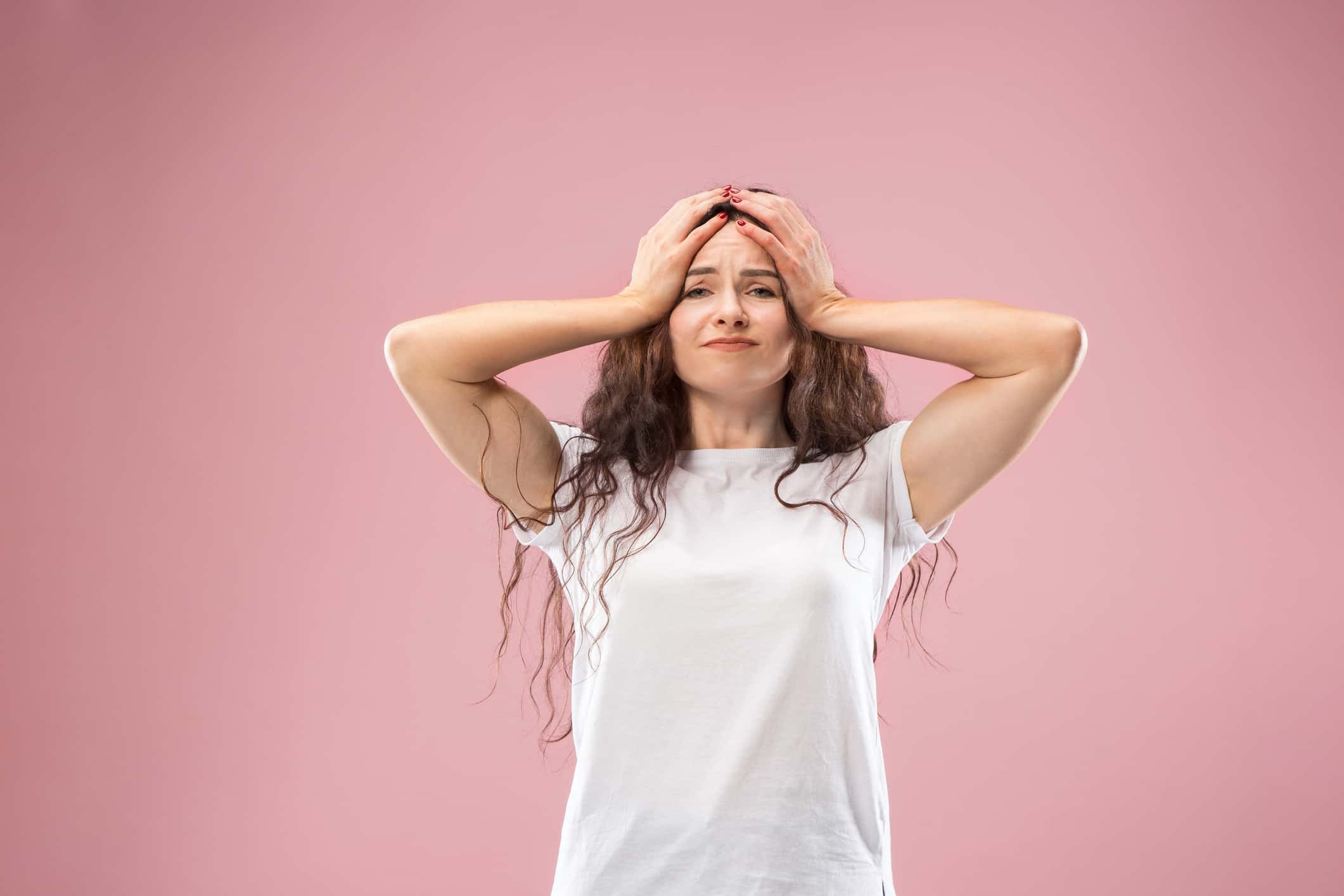 Woman having headache. Isolated on pink background. Businesswoman standing with pain isolated on trendy studio background.