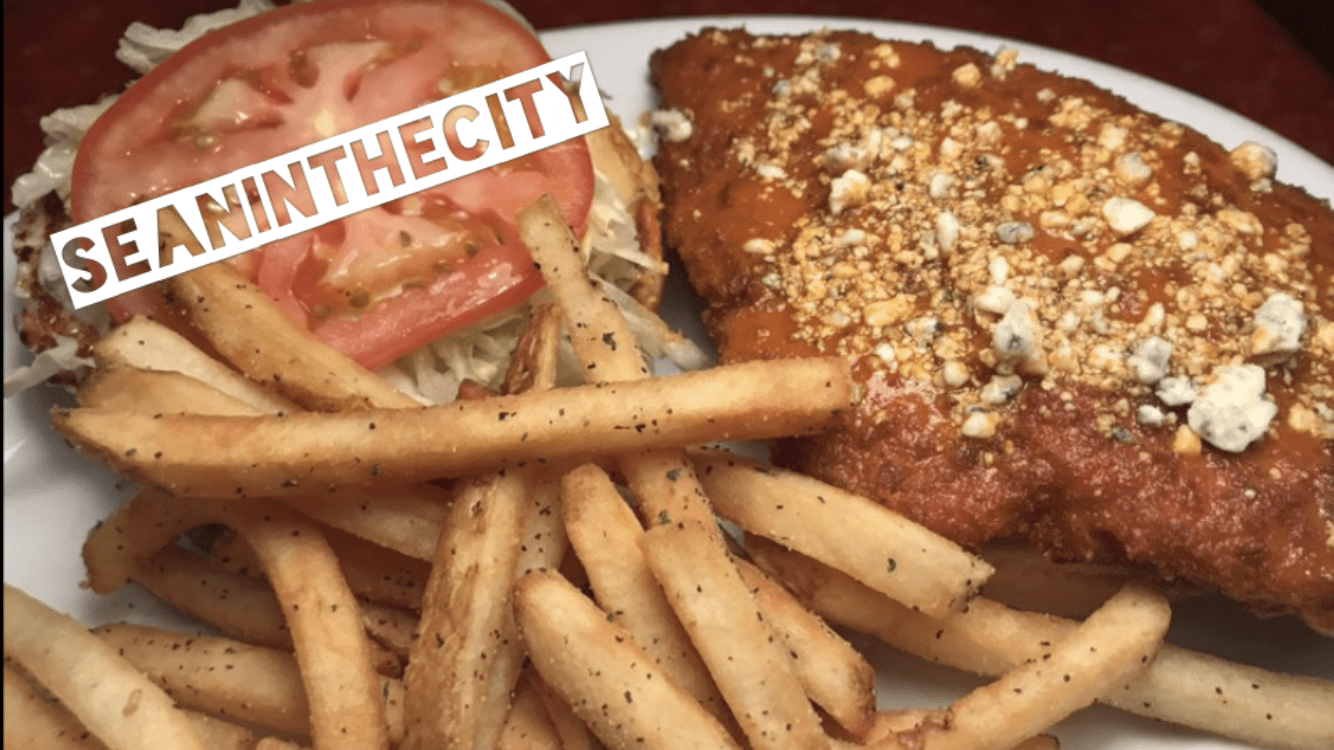 A buffalo chicken sandwich plated with french fries