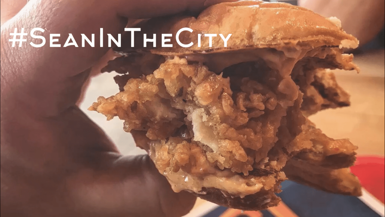 A hand holding a piece of a fried chicken sandwich