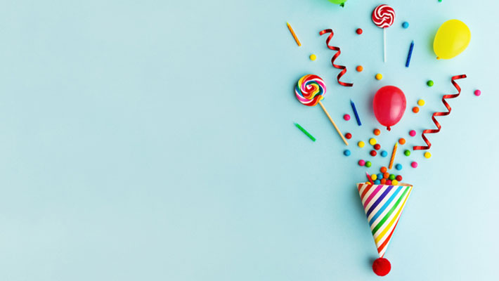 Party hat with candy, balloons and birthday candles on light blue background