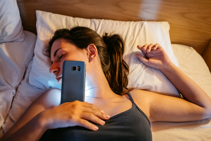 Young Woman Falling Asleep While Using Phone In The Bed At Night