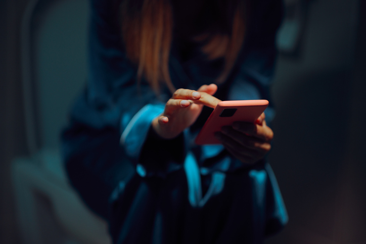 Person Checking her Phone While Sitting on the Toilet