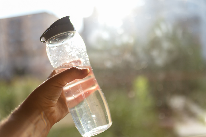 Hand holding water bottle in sunlight