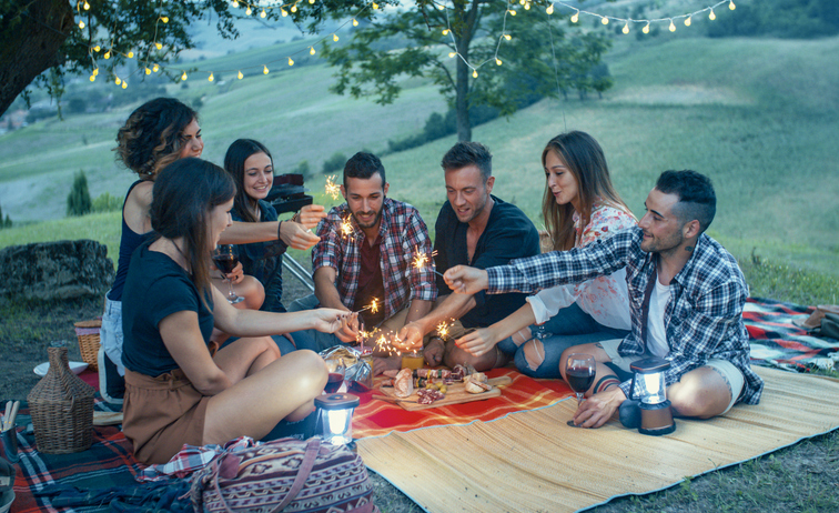 Friends celebrating with sparklers at a picnic under string lights