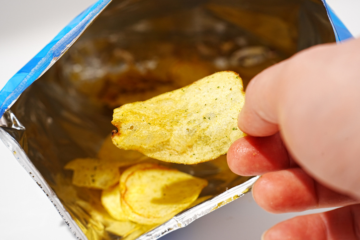potato chips in hand. potato chips with spices in a packet.