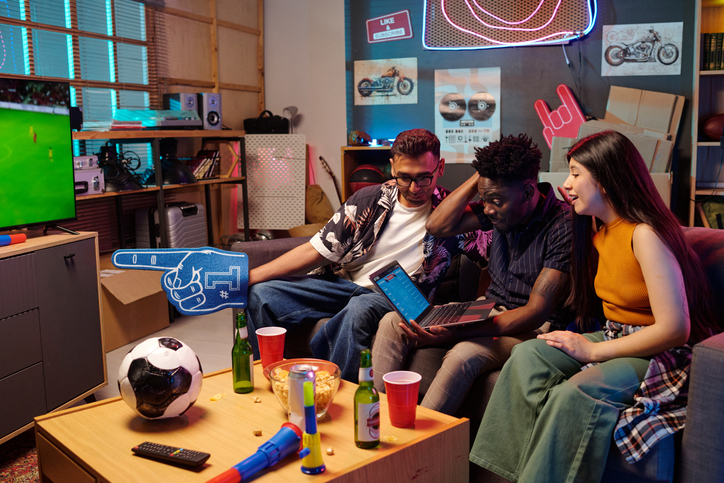 Multiethnic Young Adults Watching Soccer Match and Celebrating Together Indoors