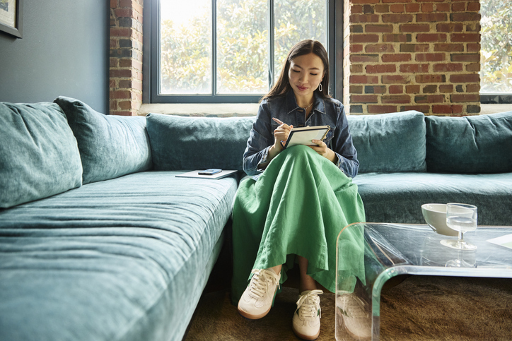 Young businesswoman writing in notebook at creative office
