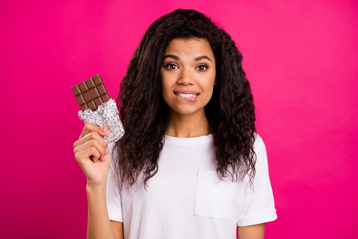 Photo of curious brunette millennial lady hold chocolate wear white t-shirt isolated on pink color background