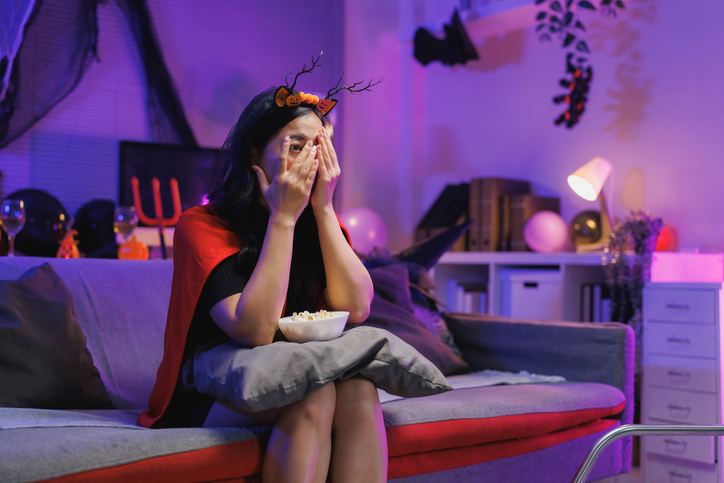 Woman watching scary movie at home on halloween night